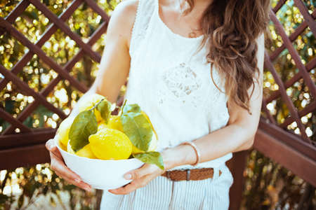 Closeup on woman in white shirt with plate of local farm lemons in the patio.の写真素材