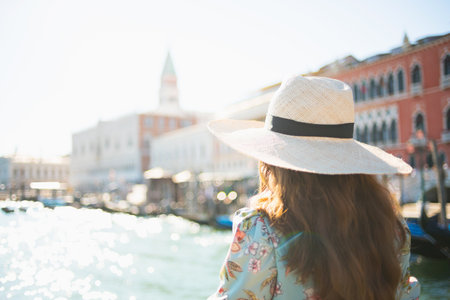 happy elegant solo tourist woman in floral dress with hat having excursion at San Marco square in Venice, Italy.の写真素材