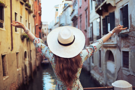 smiling trendy woman in floral dress with hat at Piazza San Marco in Venice, Italy.の写真素材