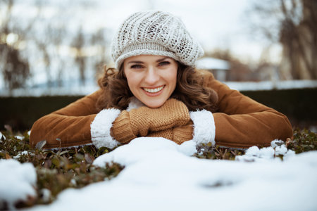 smiling elegant 40 years old woman with mittens and cup of tea in a knitted hat and sheepskin coat...