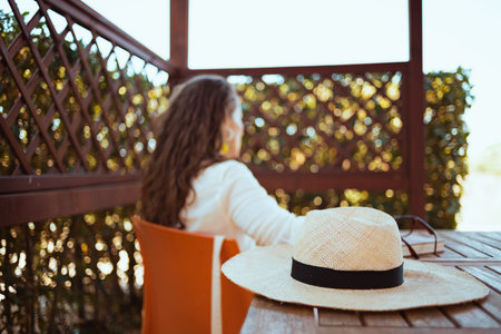 happy 40 years old woman in white shirt with hat using video chat on a smartphone in the terrace.