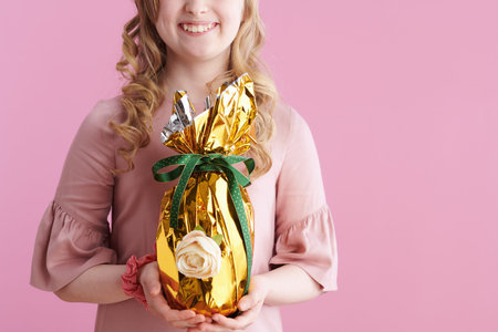 smiling stylish girl in pink dress with bunny ears showing thumbs up isolated on pink background.