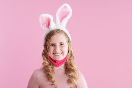 Closeup on happy child with long wavy blond hair with tulips bouquet isolated on pink.