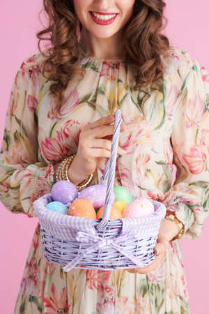 stylish middle aged woman with long wavy brunette hair with bunny ears and easter egg isolated on pink.の写真素材