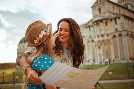 smiling stylish mother and daughter with pizza near Leaning Tower in Pisa, Italy.の写真素材