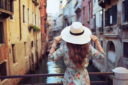 happy young traveller woman in floral dress with hat on Accademia bridge in Venice, Italy.の写真素材