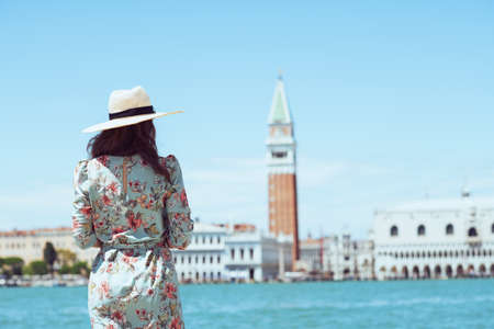 happy young traveller woman in floral dress with hat on Accademia bridge in Venice, Italy.の写真素材