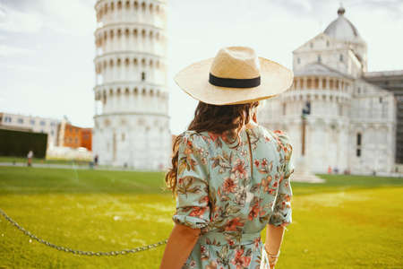 smiling young woman in floral dress with retro camera and hat in piazza dei miracoli in Pisa, Italy.の写真素材