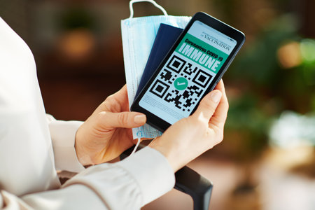 Upper view of 40 years old woman with antiseptic, wheel bag, air tickets, medical mask, spf, bikini and covid passport packing trolley bag in the modern living room in sunny day.の写真素材