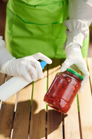 Closeup on housewife in green apron in modern kitchen disinfecting groceries after supermarket.