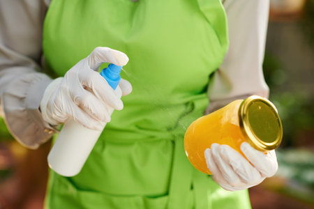 Closeup on housewife in green apron in modern kitchen disinfecting groceries after supermarket.