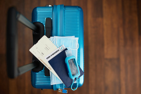 Travel during covid-19 pandemic. trolley bag with smartphone, covid passport app, medical mask and air ticket on the floor.の写真素材
