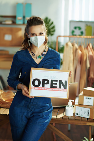 smiling modern small business owner woman in the office using smartphone.