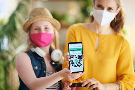 Travel during  pandemic. modern mother and child travellers with trolley bag, air tickets, medical mask and covid passport at modern home in sunny day.の写真素材