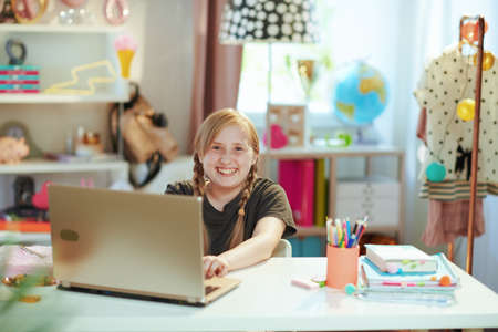 happy modern girl in grey shirt with laptop learning online at home in sunny day.の写真素材