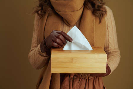 Hello september. trendy middle aged housewife in sweater with paper handkerchiefs, nasal sprey and leather gloves against bronze background.の写真素材