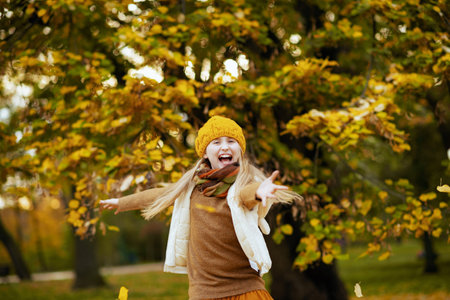 Hello september. Closeup on smiling girl in brown sweater and orange hat showing mushroom outside in...