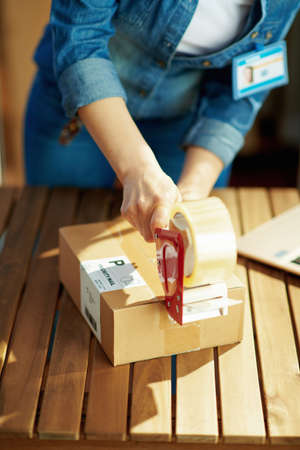 Delivery business. happy young female in jeans with parcels using smartphone app in the warehouse.の写真素材
