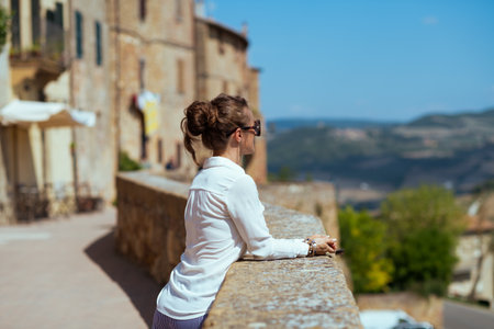 Travel in Italy. Seen from behind stylish middle aged traveller woman with straw bag having excursion in Pienza in Tuscany, Italy.の写真素材