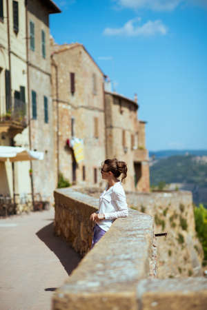 Travel in Italy. Seen from behind stylish middle aged traveller woman with straw bag having excursion in Pienza in Tuscany, Italy.の写真素材