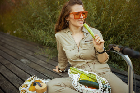 happy trendy woman in overall with string bag against black wood wall outdoors in the city.の写真素材