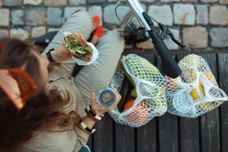 happy trendy woman in overall with string bag against black wood wall outdoors in the city.の写真素材