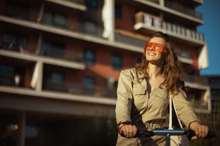 happy trendy woman in overall with string bag against black wood wall outdoors in the city.の写真素材