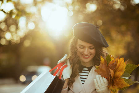 Hello autumn. dreamy trendy woman in beige trench coat with autumn yellow leaves at Old Town Square in Prague.の写真素材