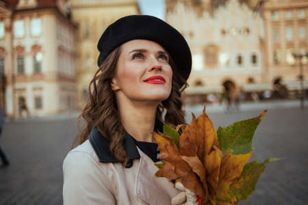 Hello autumn. dreamy trendy woman in beige trench coat with autumn yellow leaves at Old Town Square in Prague.の写真素材