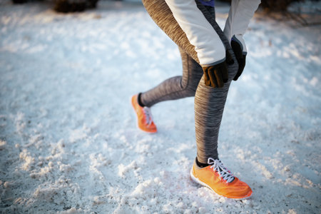 Full length portrait of young woman in white jacket workout outside in the city park in winter.の写真素材