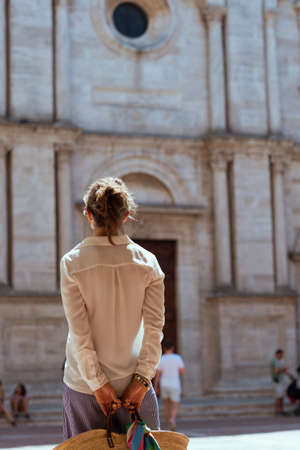 Travel in Italy. Seen from behind modern middle aged traveller woman in Tuscany, Italy enjoying promenade near cathedral in Pienza.の写真素材