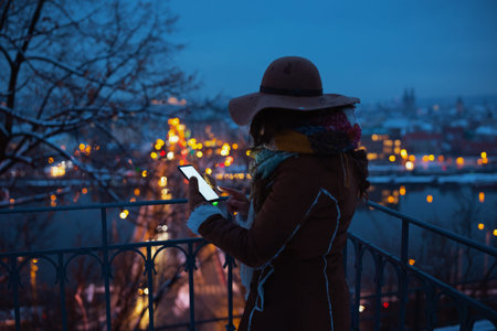 smiling modern 40 years old woman in brown hat and scarf outdoors in the city park in winter in...