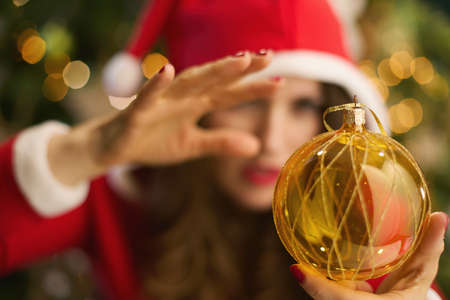 Christmas time. trendy woman with Santa hat and festive hot chocolate cocktail making online shopping on e-commerce website on a laptop near Christmas tree at modern home.の写真素材