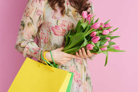 Portrait of stylish 40 years old woman in floral dress with glass of water isolated on pink.の写真素材