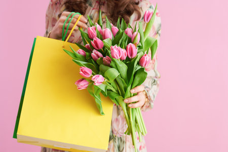 Portrait of stylish 40 years old woman in floral dress with glass of water isolated on pink.の写真素材