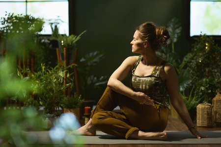 Closeup on female with yoga mat doing yoga in the green living room.の写真素材
