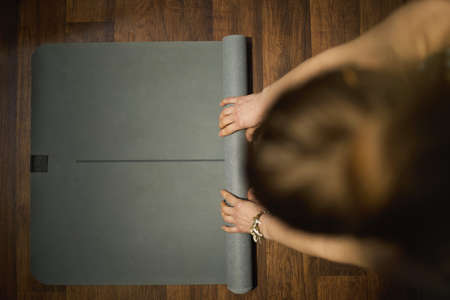 Closeup on female with yoga mat doing yoga in the green living room.の写真素材