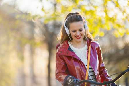 Seen from behind woman in red rain coat outside in the city riding bicycle.
