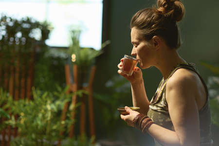 modern woman with smartphone listening to the music with headphones in the modern green house.の写真素材