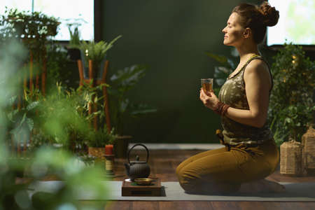 modern woman with smartphone listening to the music with headphones in the modern green house.の写真素材