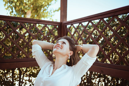 relaxed 40 years old woman in white shirt in the terrace of guest house hotel.の写真素材