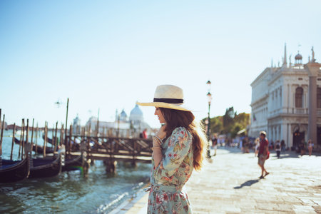 happy elegant tourist woman in floral dress with sunglasses and hat having excursion at San Marco square in Venice, Italy.の写真素材