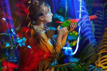 happy stylish child with toy gun and futuristic glasses in metaverse.