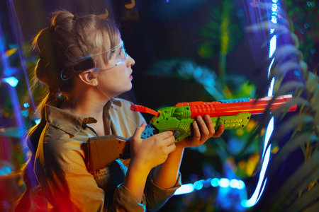 happy stylish child with toy gun and futuristic glasses in metaverse.の写真素材