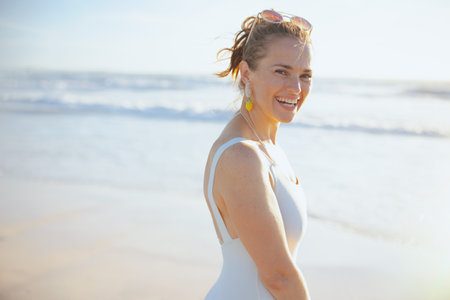 Portrait of smiling elegant 40 years old woman in white swimwear at the beach.の写真素材