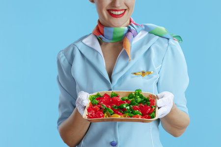 Closeup on happy female stewardess against blue background in blue uniform with candies.の写真素材
