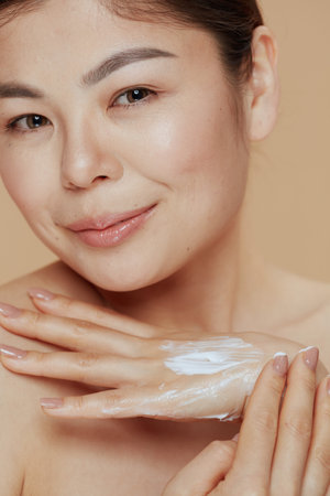 modern woman with hand cream on beige background.の写真素材