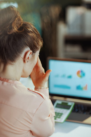 Seen from behind modern woman with calculator and laptop in modern office.の写真素材