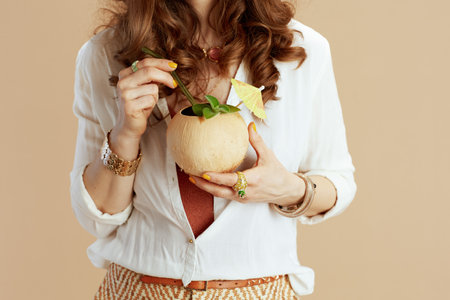 Beach vacation. Closeup on woman against beige background with coconut cocktail.の写真素材
