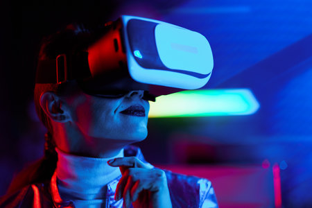 Neon metaverse futuristic concept. pensive stylish woman in vr headset on dark background.の写真素材